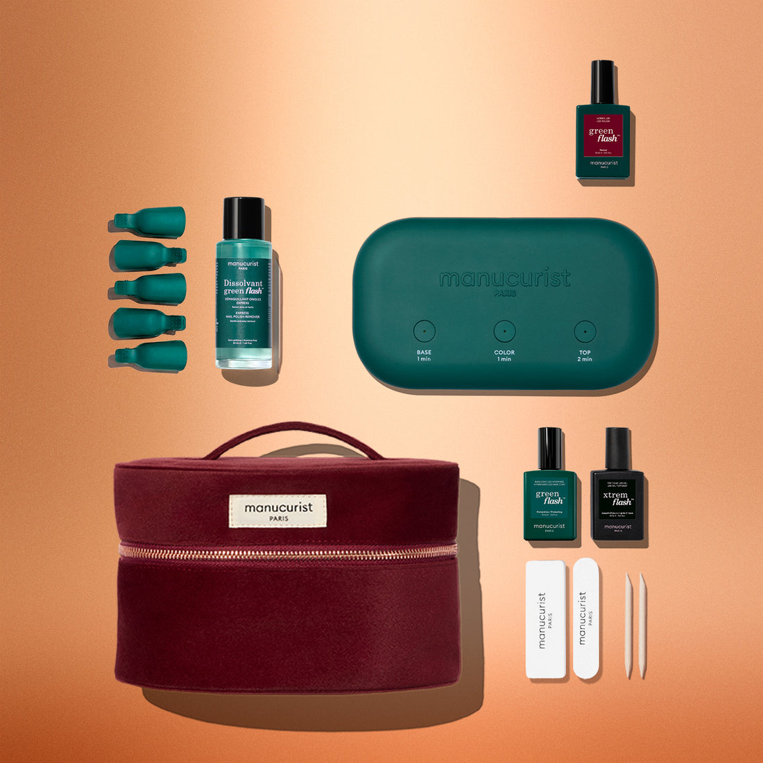 The Manucurist Green Flash™ Discovery Kit Gift Set, featuring a stylish red velvet case, teal lamp, gel nail polishes, essential nail care products, files, and cuticle tools arranged neatly on an orange background—everything you need for a salon-style manicure at home.