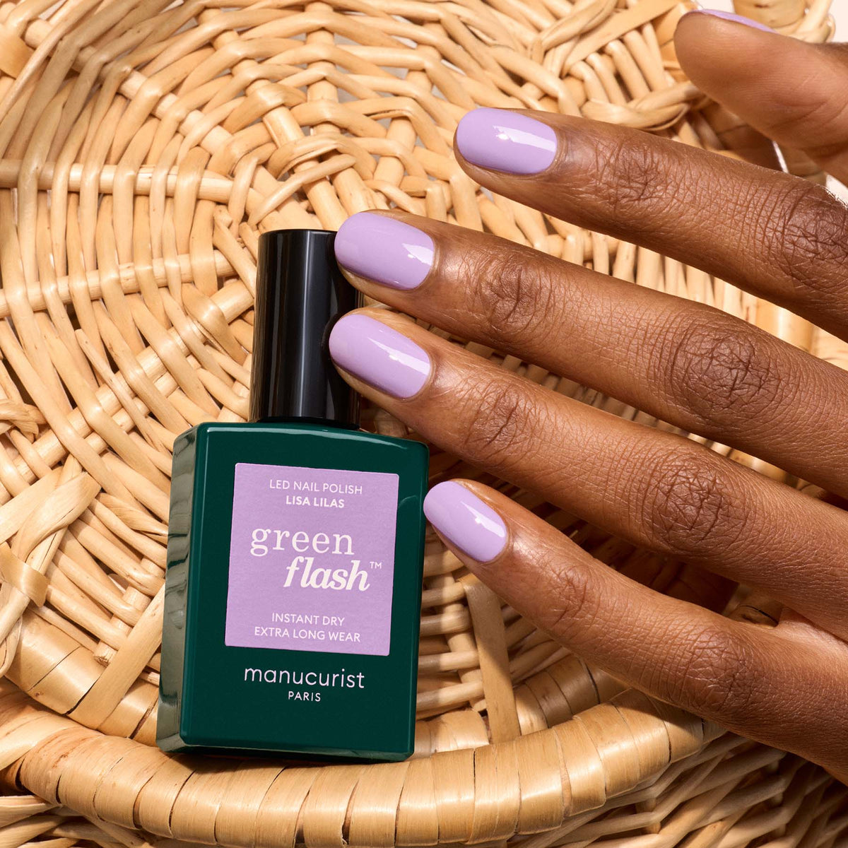 Une main aux ongles soigneusement manucurés, couleur violet clair, repose sur un panier tressé à côté d&