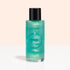 Un flacon transparent avec un bouchon noir, étiqueté « Manucurist Green Flash™ Gentle Glitter Remover », contient un liquide bleu sarcelle scintillant, sans acétone, et est présenté sur un fond pêche clair et blanc.