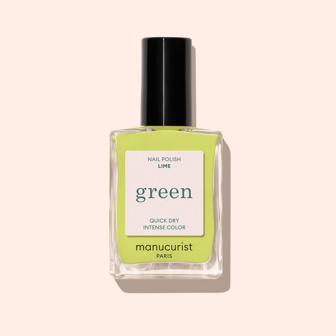 A clear glass bottle of bright anise green nail polish called Lime by Manucurist, with a black cap, is placed on a light beige background.