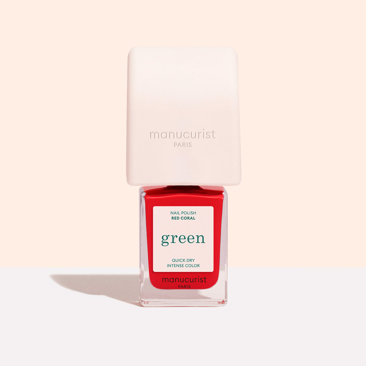 A bottle of Manucurist US Mani Helper stands on a light background, featuring a square pink cap and clear bottle with a red label—perfect for achieving a flawless manicure.