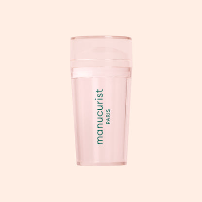 A translucent pink Mani stamper by Manucurist US, ideal for French tips, features "manucurist PARIS" in vertical green print on the front and is displayed against a pale peach background.
