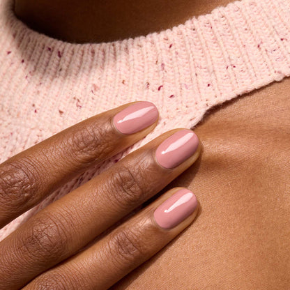 A close-up of a hand with short, neatly manicured nails painted in Manucurist’s Old Rose from the Green™ range, resting on a person&