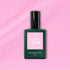 A bottle of Manucurist Candy Green Flash LED nail polish, with a pink label and dark green body, sits on a light pink background—ideal for those who love cool-toned LED manicures.