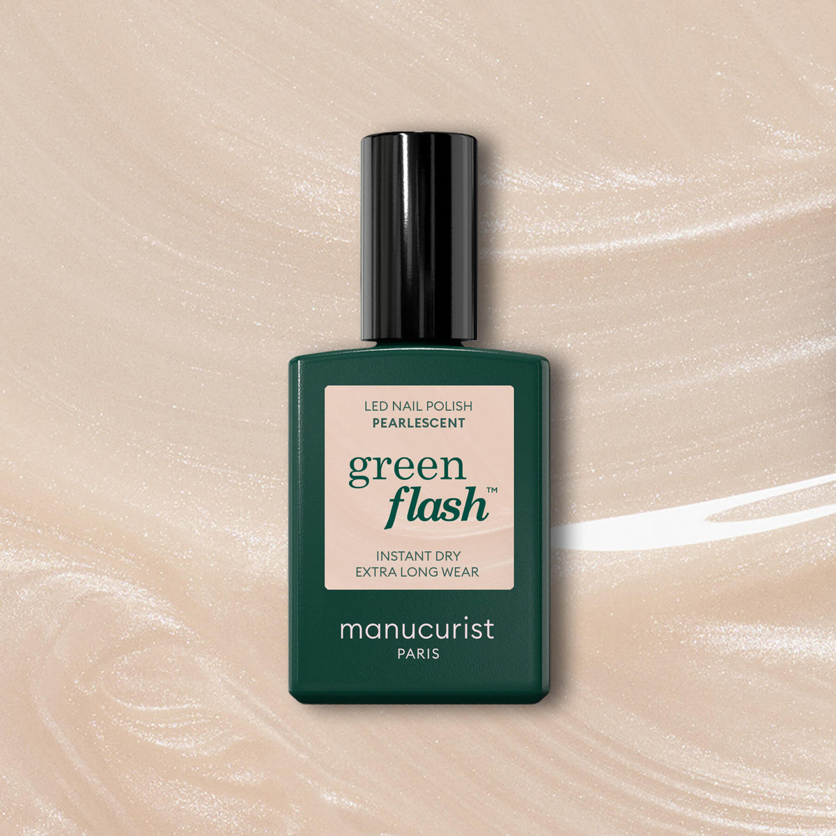 Un flacon de vernis à ongles Pearlescent de Manucurist, avec un bouchon et une étiquette vert foncé, repose sur un fond gel beige scintillant. L’étiquette indique : « green flash, séchage instantané, tenue extra longue, manucurist Paris. »