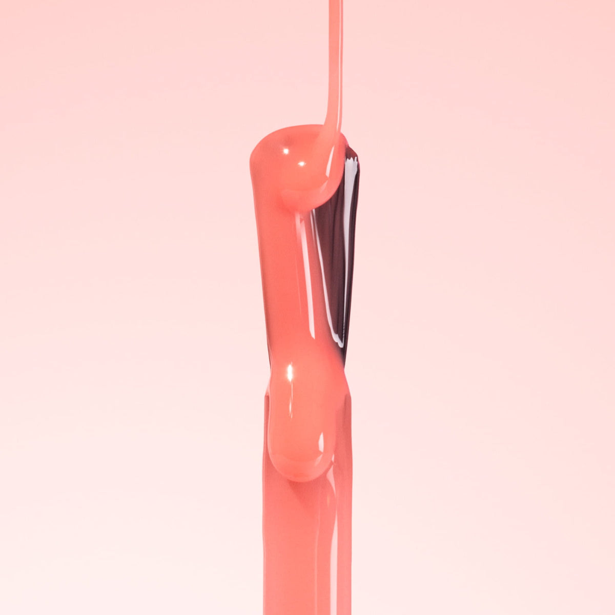 Pink nail polish is being poured from a brush, creating a smooth, glossy stream against a soft pink background.