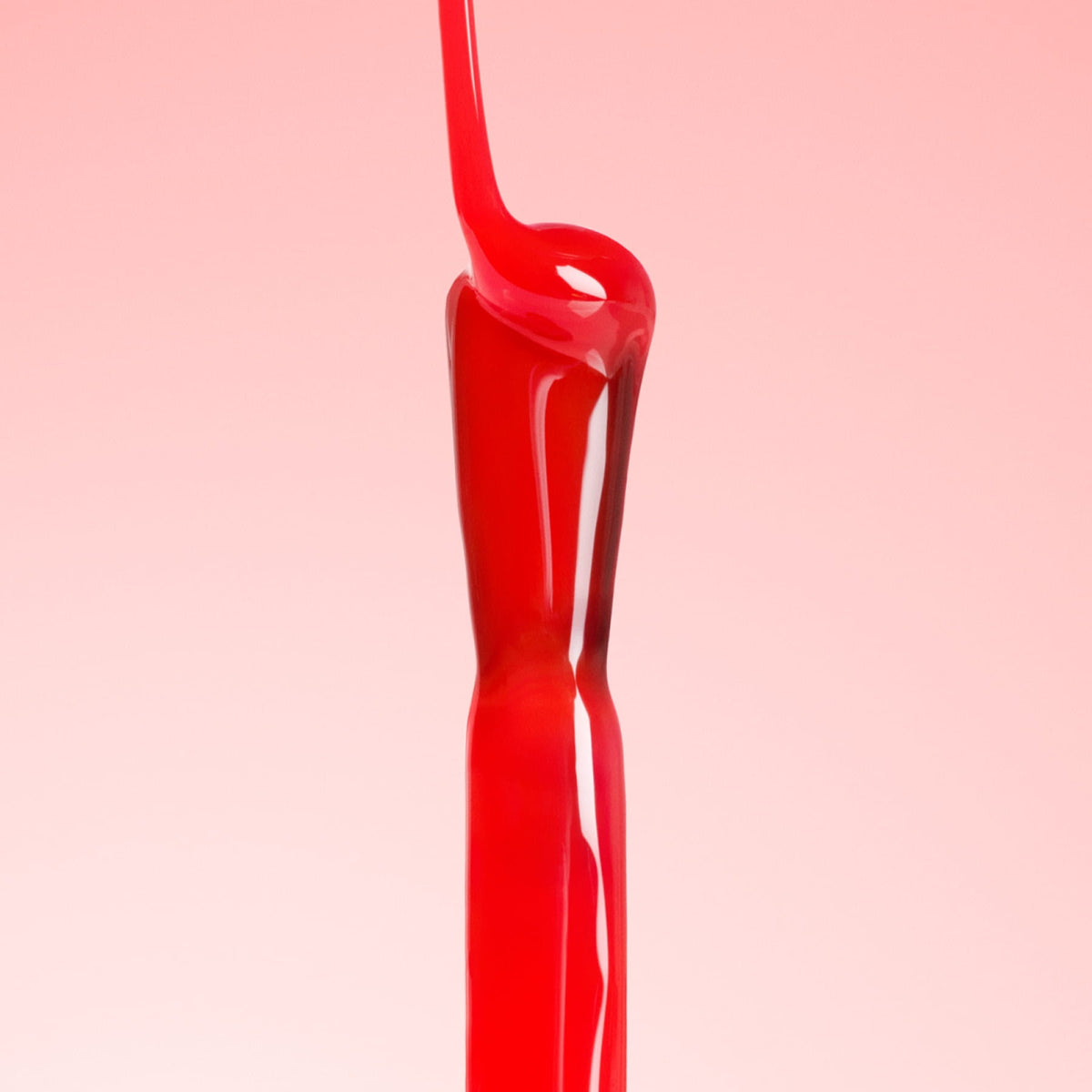 A stream of glossy red liquid pours and twists against a light pink background, creating a smooth, abstract shape.