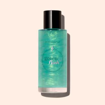 Un flacon de dissolvant doux pour paillettes Green Flash™ de Manucurist avec un bouchon noir, contenant un liquide vert clair enrichi en huile de ricin, est présenté sur un fond beige clair.