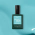 A green bottle of Manucurist Riviera gel polish rests on a teal surface, displaying its Instant Dry and Extra Long Wear features.