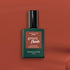A bottle of Manucurist Brique Green Flash LED nail polish sits on a warm brown background. The dark green bottle with black cap and terracotta-accented label hints at the brick red shade inside.