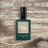 A bottle of Manucurist Metallic nail polish sits on a glittery surface that echoes the cool-toned gold shimmer and metallic highlights of the polish.