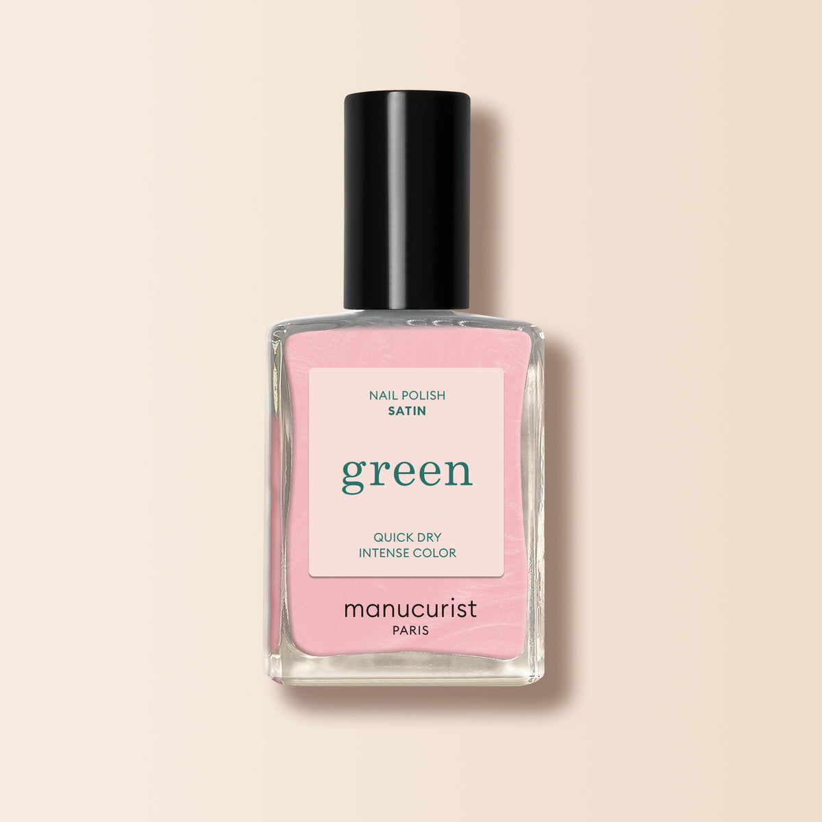 A bottle of Manucurist Satin nail polish with a black cap, featuring pale pink, pearlescent color. The label reads "green" and "quick dry intense color," shown on a light beige background.