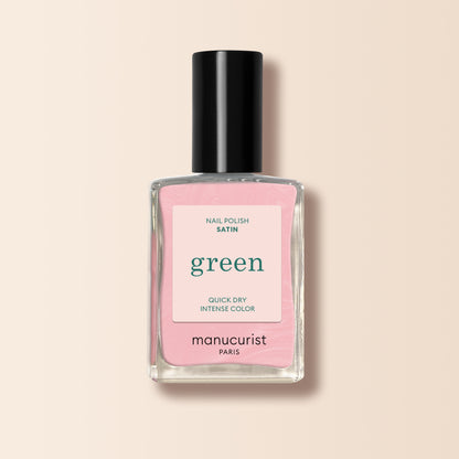 A bottle of Manucurist Satin nail polish with a black cap, featuring pale pink, pearlescent color. The label reads "green" and "quick dry intense color," shown on a light beige background.