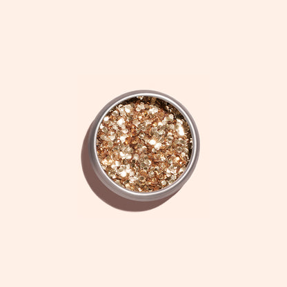Un pot rond de paillettes biodégradables Rose Gold de Manucurist, parfaites pour le Nail Art, est posé sur un fond beige clair et projette une ombre douce.