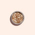 Un pot rond de paillettes biodégradables Rose Gold de Manucurist, parfaites pour le Nail Art, est posé sur un fond beige clair et projette une ombre douce.