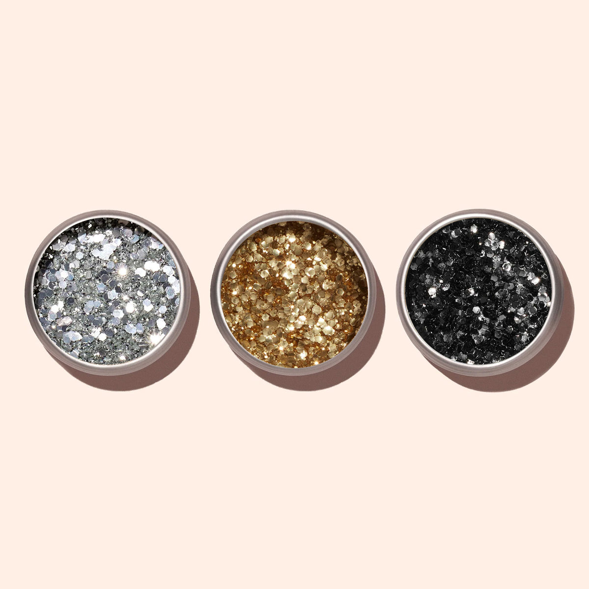 Three small round containers of Manucurist Silver Biodegradable Glitter are arranged in a row on a light beige background—ideal for eco-friendly nail polish or dazzling silver nail art.