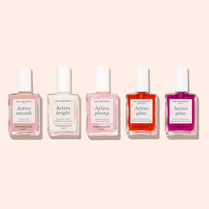 Cinq flacons de soins pour les ongles Manucurist — Active™ Smooth 01, Active Bright, Active Plump, Active Glow (orange) et Active Glow (rose) — sont joliment alignés sur un fond beige clair. Ces formules d&