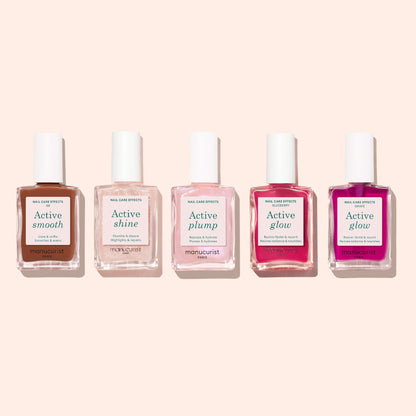 Five bottles of Manucurist nail care, including Active Smooth 03, are arranged in a row on a light beige background. Each bottle features a white cap and differently colored liquid, with labels: Active Smooth, Shine, Plump, Glow, and Glow.