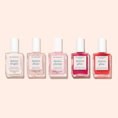 Five bottles of Manucurist nail care products are arranged in a row on a light pink background, each labeled with different effects: Active™ Bright, Shine, Plump, and two bottles of Glow. These bio-based essentials from Manucurist are ideal for anyone seeking effective nail care and a nourishing nail strengthener in their routine.