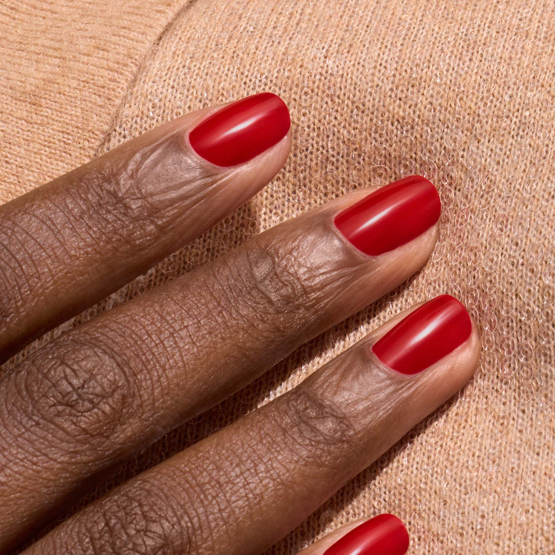 A close-up of a hand with dark skin and neat nails painted in Manucurist&