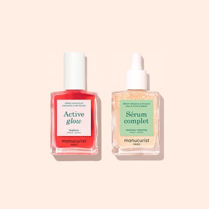 Deux flacons de la Routine Basic de Manucurist - Sensitive Nails — un vernis à ongles Active Glow rouge vif avec un bouchon blanc et un sérum pour cuticules Serum Complet transparent avec compte-gouttes — sont joliment disposés sur un fond pêche clair, offrant le duo parfait pour le soin des ongles et des ongles hydratés.