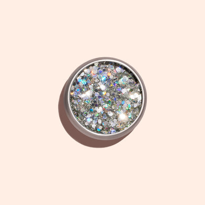 A round container of Manucurist Biodegradable Holo Glitter, seen from above on a light beige background with a soft shadow—ideal for adding eco-friendly sparkle to your next nail art design.