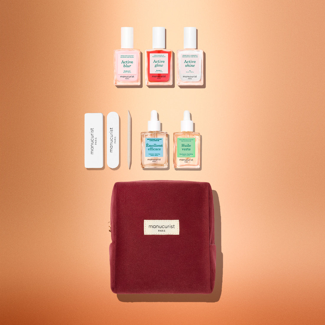 The Manucurist Active™ Starter Kit Gift Set features everything you need to elevate your manicure routine: three nail polishes, two cuticle oils, two nail files, and a wooden cuticle stick, all beautifully packaged in a burgundy velvet pouch and arranged on a soft peach background.