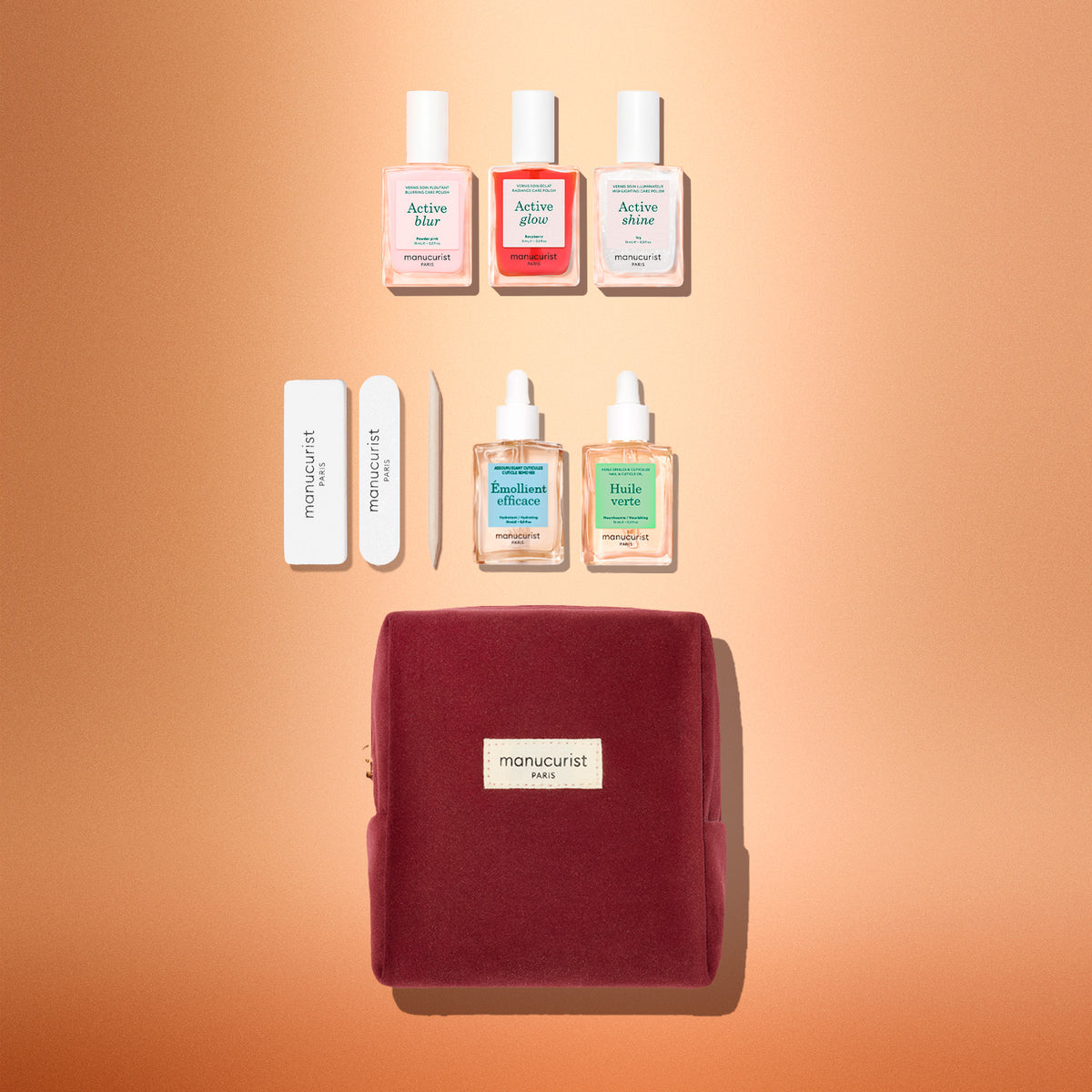 The Manucurist Active™ Starter Kit Gift Set features everything you need to elevate your manicure routine: three nail polishes, two cuticle oils, two nail files, and a wooden cuticle stick, all beautifully packaged in a burgundy velvet pouch and arranged on a soft peach background.