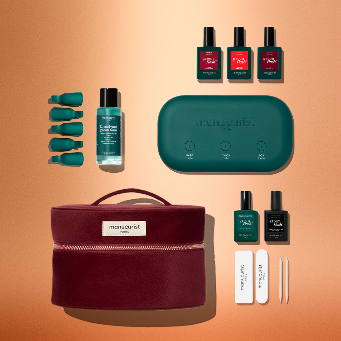 A flat lay of the Manucurist Green Flash™ Starter Kit Gift Set, featuring nail polish bottles, remover, green-capped accessories, a teal nail lamp, nail files, and tweezers—all arranged beside a burgundy zippered pouch on a gradient peach background—perfect for achieving salon-quality manicures at home.