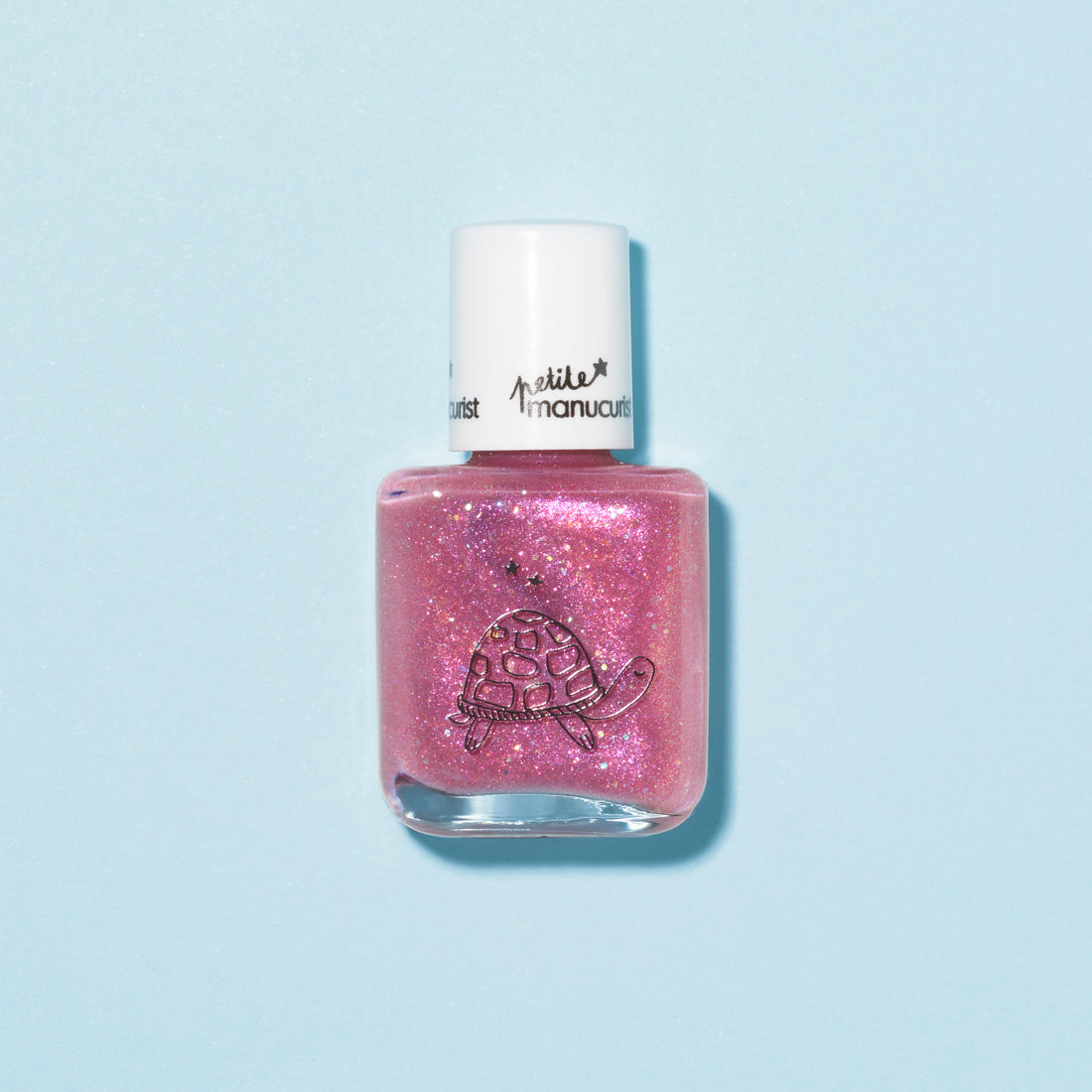 Un flacon transparent du vernis à ongles pailleté rose framboise pour enfants « Betty the Turtle » de Manucurist, avec un bouchon blanc et une illustration de tortue, sur fond bleu clair. S’enlève facilement à l’eau savonneuse pour un nettoyage simple.