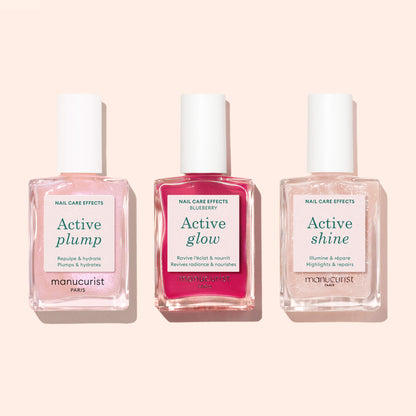 Trois flacons de soins pour les ongles d’origine végétale Manucurist, dont Active™ Plump Pink Glazed, Active Glow et Active Shine, sont alignés côte à côte sur un fond rose pâle — le trio idéal pour des ongles hydratés.