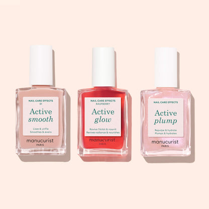 Trois flacons de soin des ongles d’origine végétale étiquetés Active™ Smooth 01 par Manucurist, contenant chacun un liquide CC Polish Treatment de couleur différente, présentés côte à côte sur un fond rose clair.