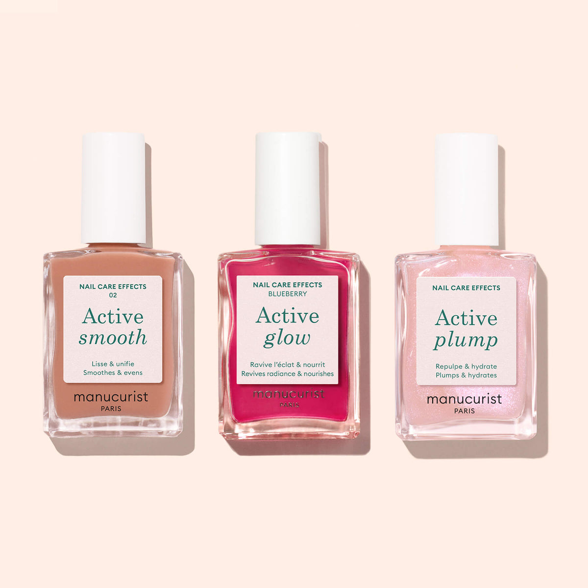 Three bottles of Manucurist nail care products—Active™ Smooth 02, Active Glow, and Active Plump—are arranged side by side on a light pink background, showcasing a luxurious nail treatment routine.