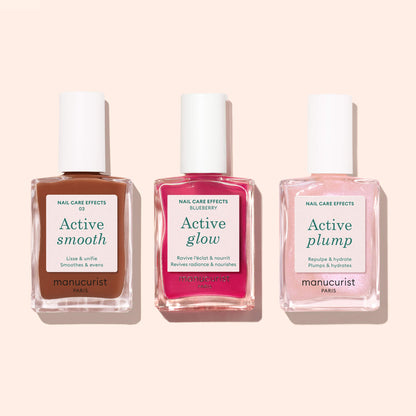 Three bottles of Manucurist Active Smooth 03 nail polish stand against a light pink background. The labels read “Active Smooth,” “Active Glow,” and “Active Plump”—a stylish trio for your nail care routine.