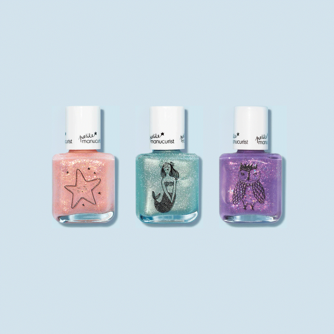 Le set Manucurist Customizable 3-pack Petite Manucurist comprend des vernis à ongles pour enfants pêche scintillant, bleu sarcelle et violet, chacun avec un bouchon blanc et de jolies illustrations noires d’étoile de mer, de sirène et de hibou sur le devant.
