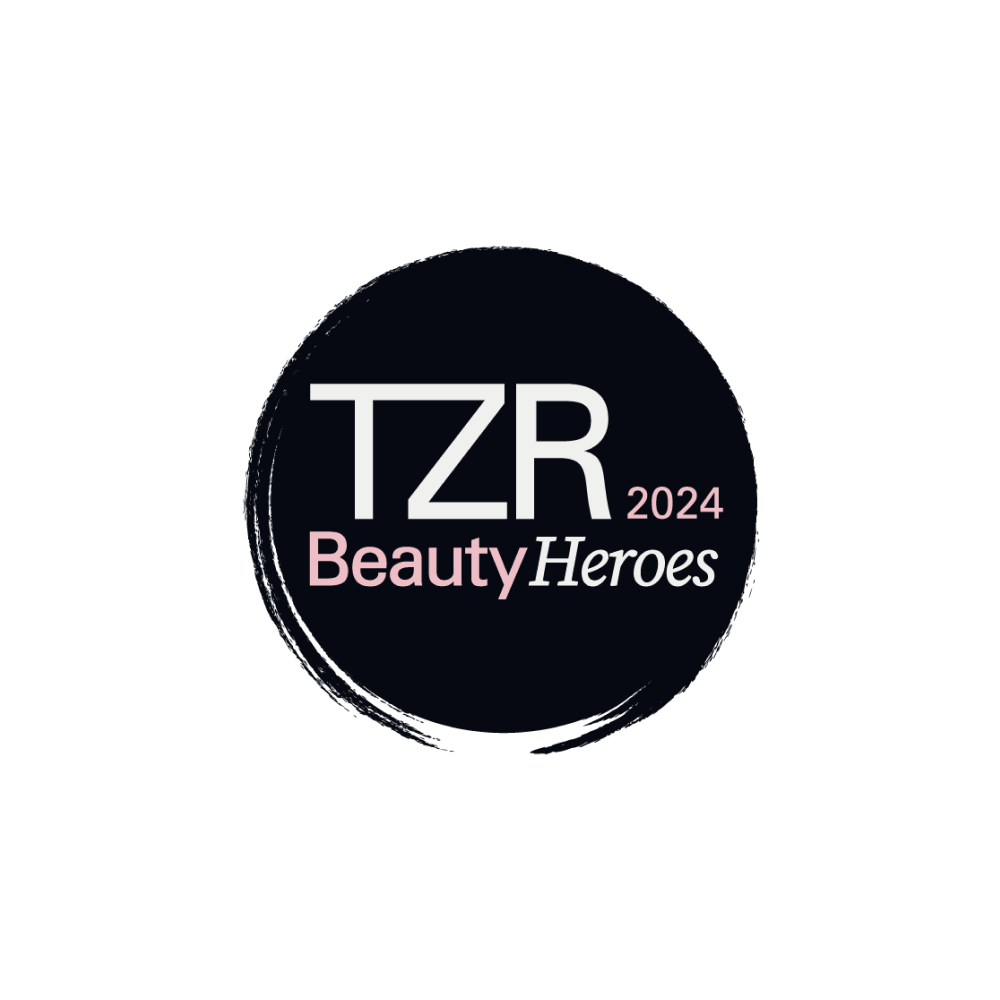 Un logo circulaire noir avec le texte TZR 2024 Beauty Heroes en blanc et rose sur un fond gris clair.