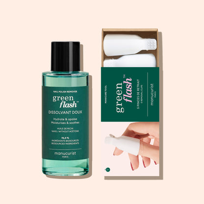 A bottle of Manucurist-us Green Flash™ Remover  Clips Duo stands beside an open box with five reusable fingertip clips, each featuring a white textured cap. The background is a soft beige color.