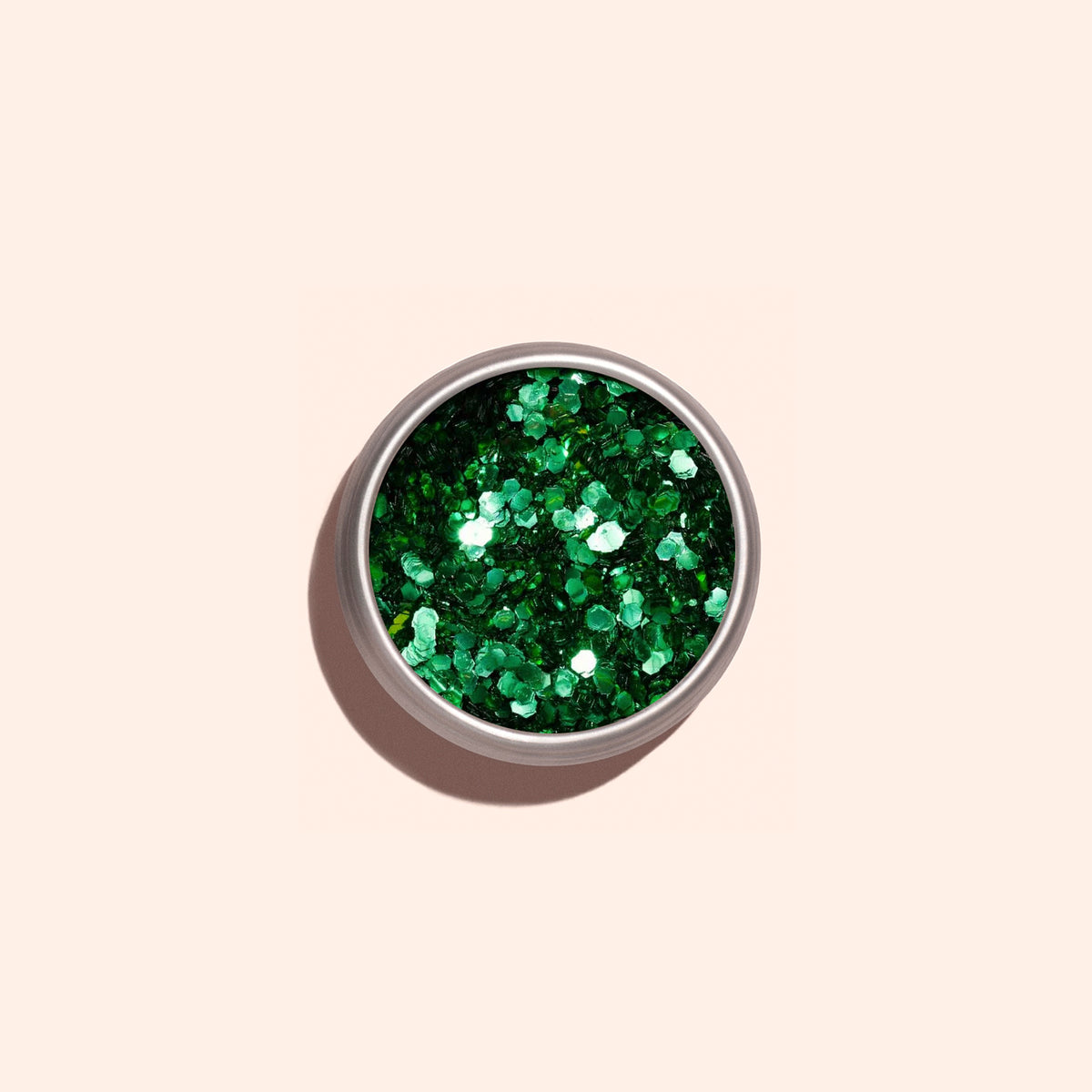 Un petit pot rond de Cactus Biodegradable Glitter de Manucurist est posé sur un fond beige clair ; ses paillettes vertes brillantes et écoresponsables projettent une ombre douce — idéal pour un nail art durable.