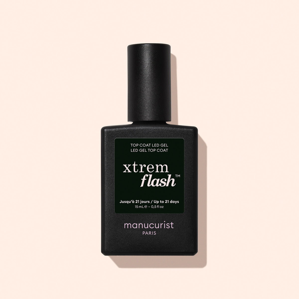 A black bottle of Manucurist Xtrem Flash™ Gel Top Coat stands against a pale pink background, featuring a dark green label with white and yellow text highlighting express removal and flawless wear.
