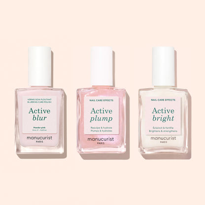 Trois flacons de vernis soin pour ongles Manucurist — Active™ Blur, Active Plump et Active Bright — sont présentés sur un fond rose clair. Ces formules innovantes mettent en avant le vernis Manucurist Active™ Blur pour un fini mat impeccable, ainsi qu&
