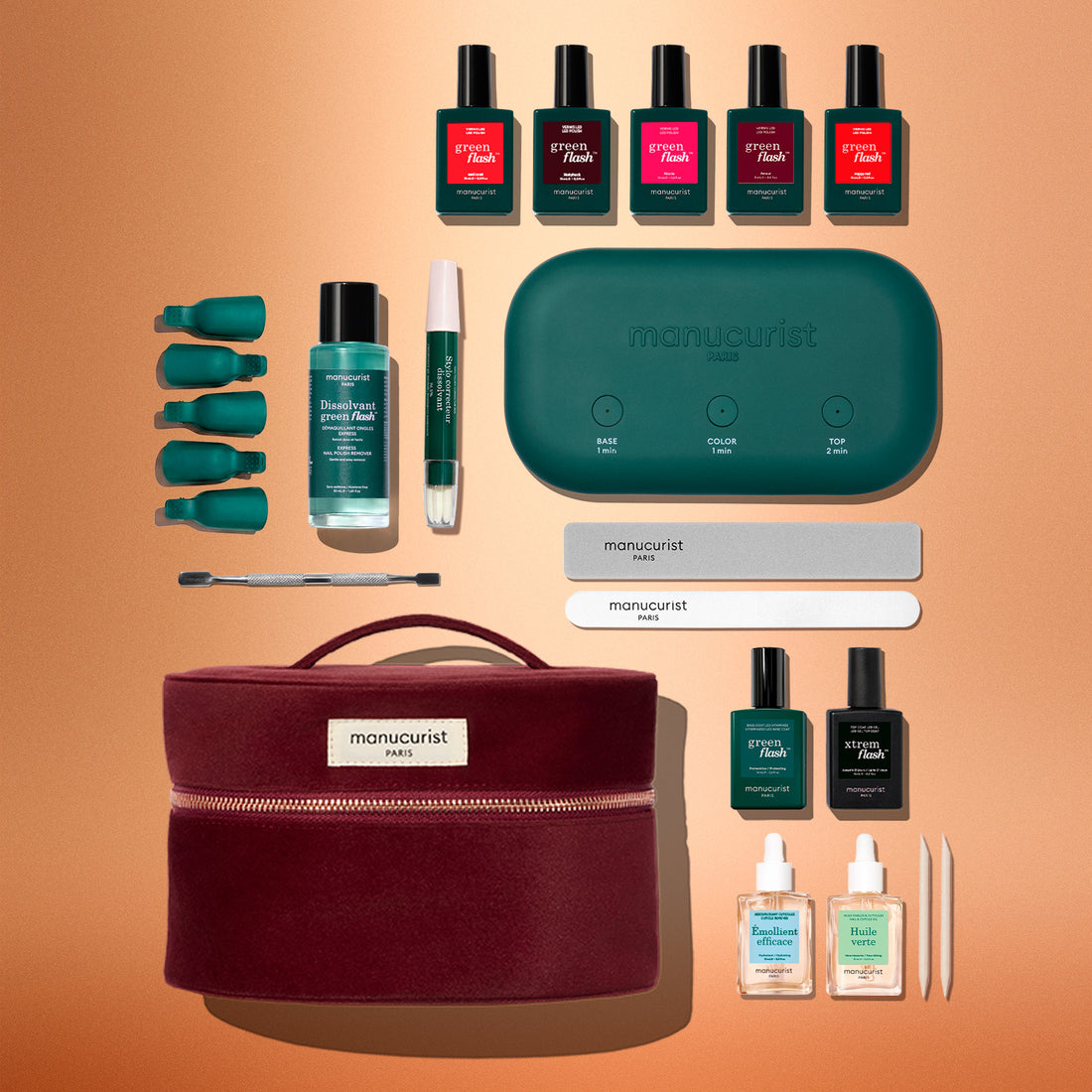 The Manucurist Green Flash™ Super Ultimate Kit Gift Set includes Green Flash gel polish, remover clips, a nail file, buffer, cuticle stick, LED lamp, base and top coats, and a burgundy carrying case—all elegantly displayed on a tan background.
