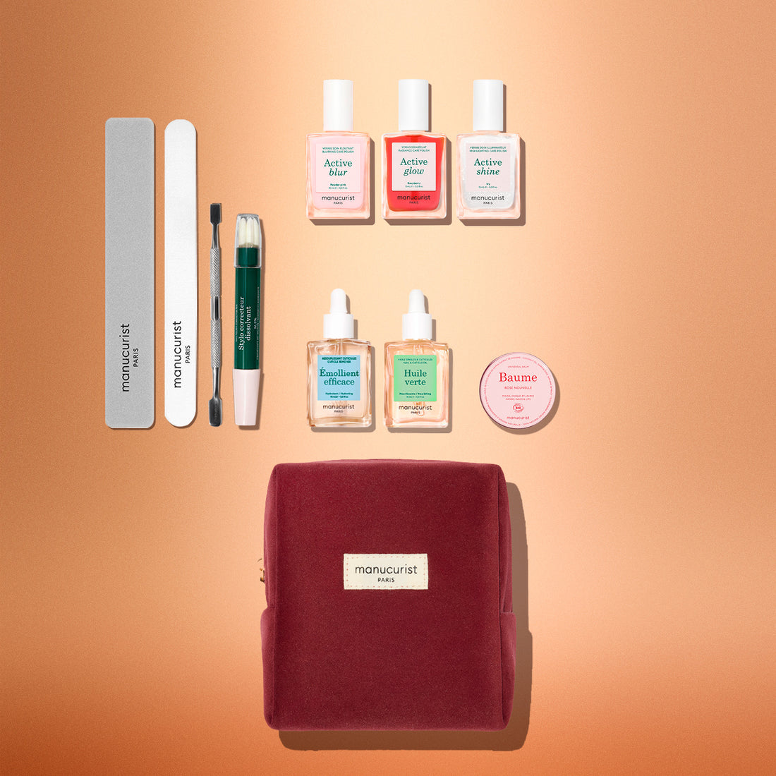 The Manucurist Active™ Ultimate Gift Set, featuring a burgundy pouch, is elegantly displayed on a peach background—surrounded by nail files, a cuticle tool, six nail care bottles, and a round balm tin—making it the perfect upgrade to your manicure routine or a thoughtful holiday gift.