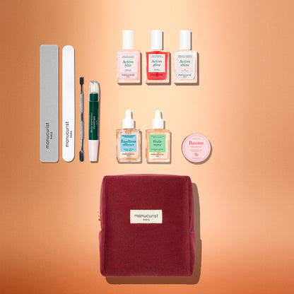 Le coffret cadeau ultime Active™ de Manucurist, avec sa pochette bordeaux, est élégamment présenté sur un fond pêche, entouré de limes à ongles, d’un accessoire pour les cuticules, de six flacons de soin pour les ongles et d’une boîte ronde de baume. De quoi enrichir votre routine manucure ou offrir un cadeau attentionné pour les fêtes.