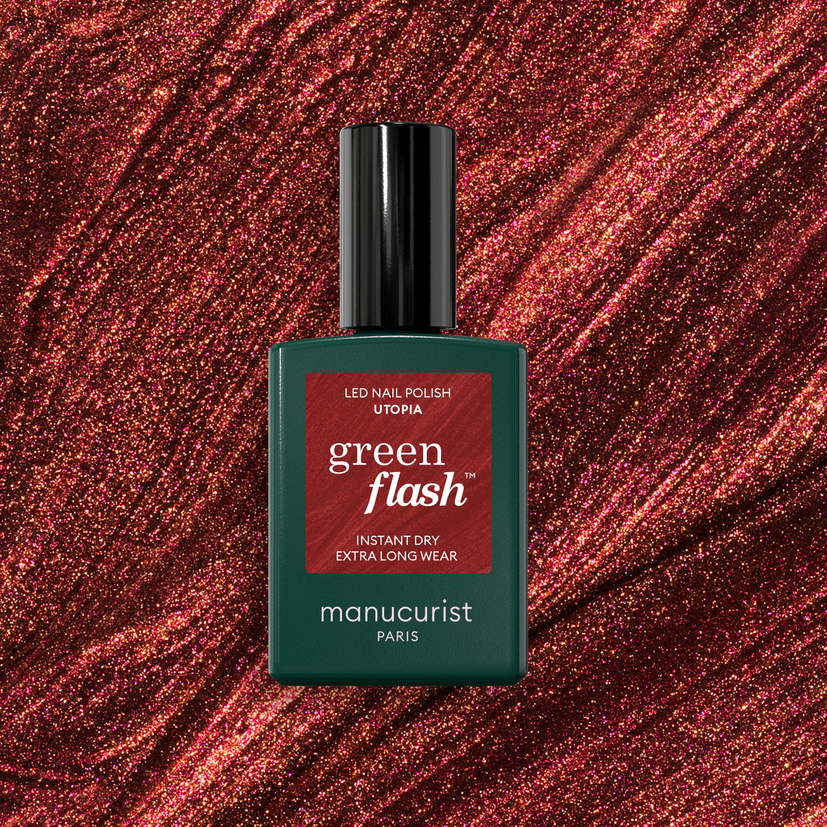 Un flacon de vernis gel Manucurist Utopia se détache sur un fond scintillant rouge profond à paillettes. Le flacon est vert foncé avec un capuchon noir et une étiquette rouge.