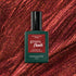 Un flacon de vernis gel Manucurist Utopia se détache sur un fond scintillant rouge profond à paillettes. Le flacon est vert foncé avec un capuchon noir et une étiquette rouge.