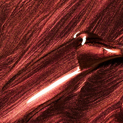 Gros plan sur Utopia de Manucurist, un vernis gel bordeaux métallique scintillant, appliqué au pinceau pour créer des vagues lisses et réfléchissantes — parfait pour les adeptes des finis brillants et métalliques.