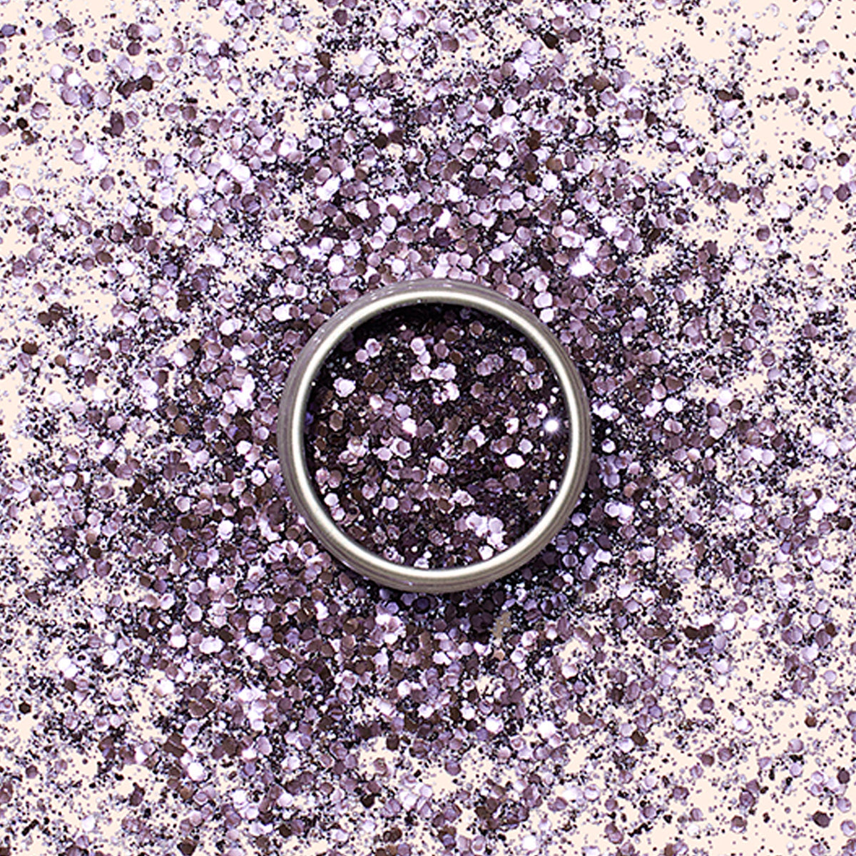 A silver ring rests on a surface sprinkled with Manucurist Biodegradable Glitter, creating a sparkling, eco-friendly backdrop reminiscent of nail art designs.