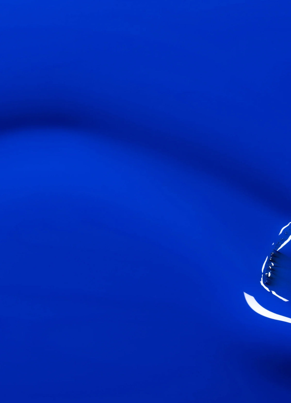 Une seule goutte d’eau crée des ondulations sur une surface bleue lisse et vive, les reflets de lumière renforçant la sensation de mouvement et de fluidité.