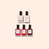 Five nail polish bottles from the Welcome kit Green by Manucurist-test are arranged in two rows on a beige background: two clear bottles above three in pink and red shades.