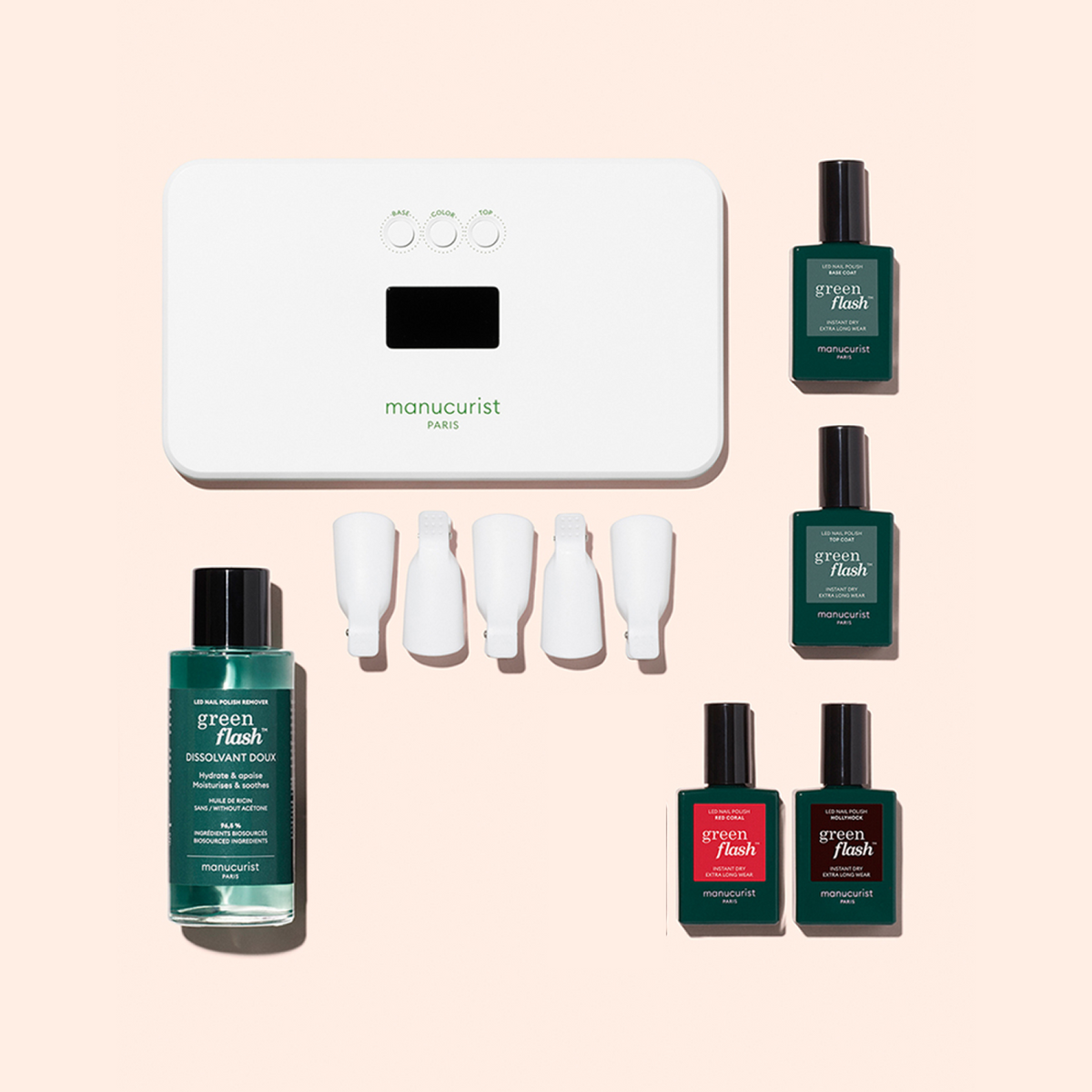 A manicure kit including a white LED lamp, four bottles of green flash nail polish in various colors, a bottle of nail polish remover, and four white nail clips arranged neatly on a pale background.